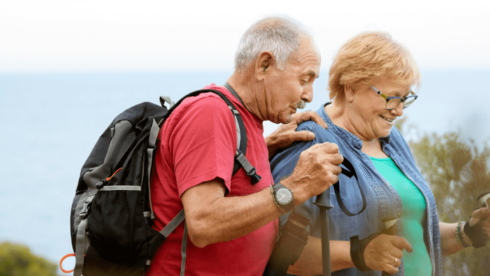 An elderly couple hike in their walking gear.