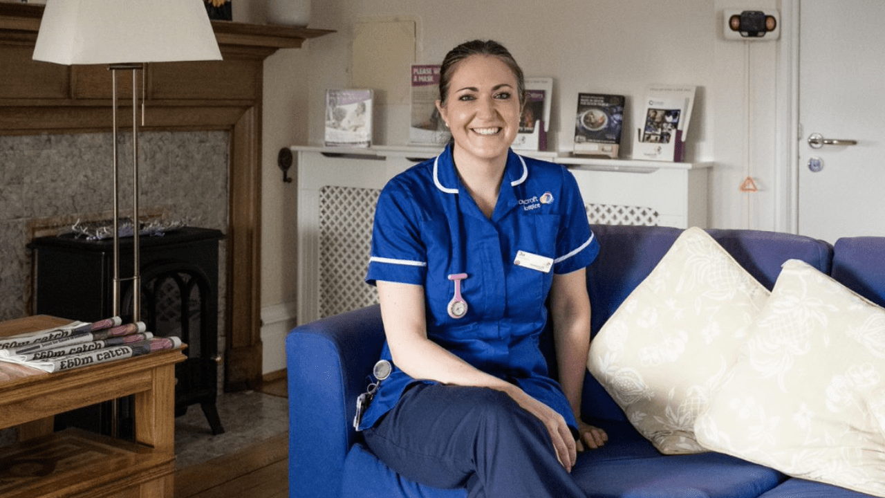 A registered nurse sitting down and smiling.