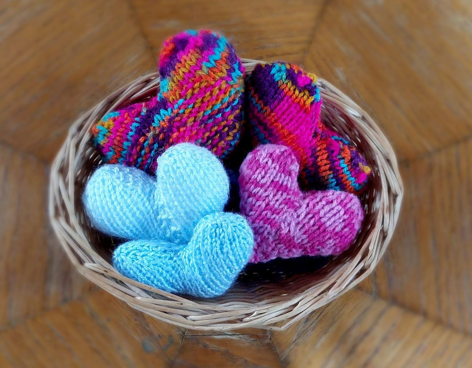 Some knitted hearts in a wicker basket.