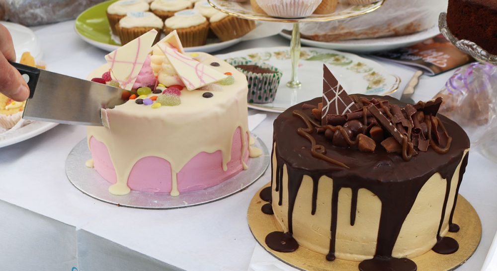 Multipul cakes somebody had baked for the Rowcroft Big Bake, they are being cut with a knife.