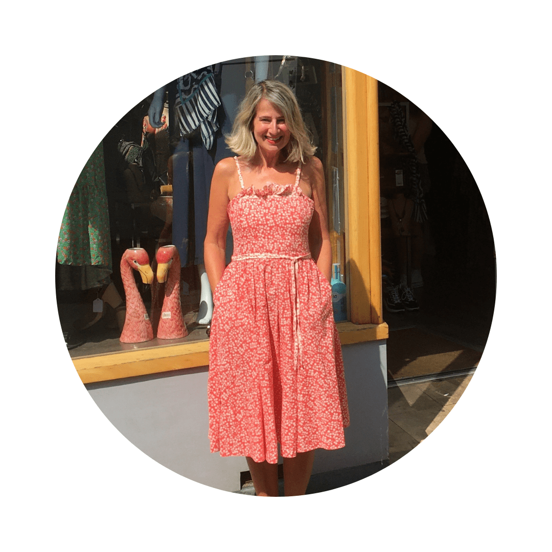 A woman in a red dress stands in front of a Rowcroft shop