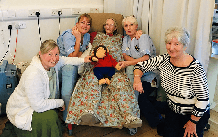A clinical staff and family members have a photograph with a patient.