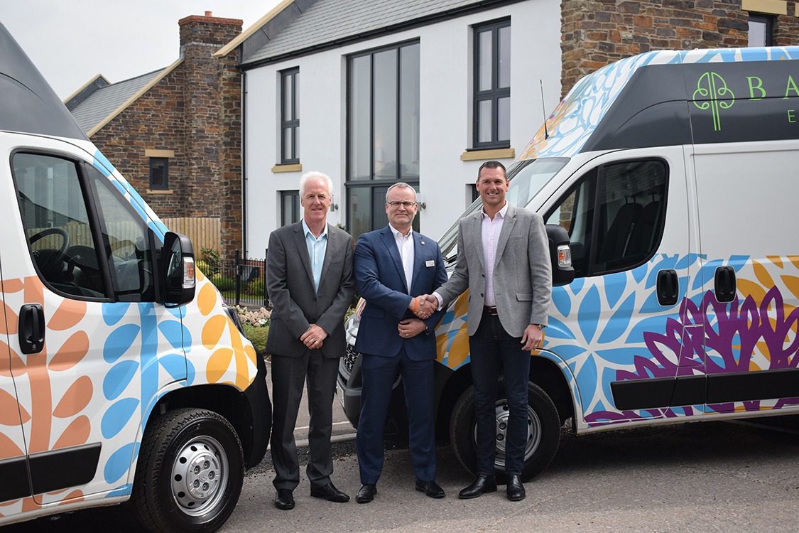 CEO Mark Hawkins stands with Baker estates representatives with the new Rowcroft vans they provided.