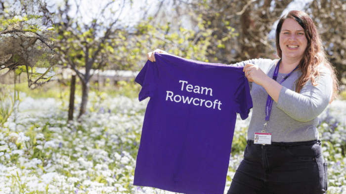 Rowcroft employee holding a Team Rowcroft tshirt.