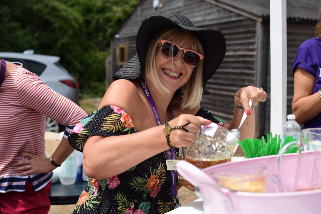 A Rowcroft employee smiles whilst stirring a drink at a Rowcroft summery garden party.