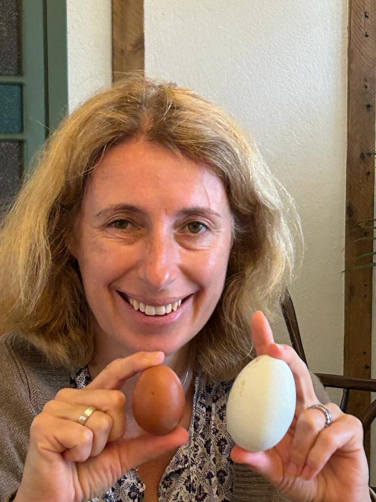 Helen Boyd smiles whilst holding two eggs.
