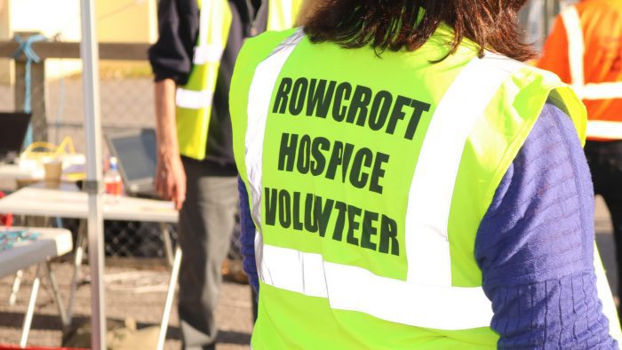 A woman volunteering at a Rowcroft event, wearing a high visibility vest.