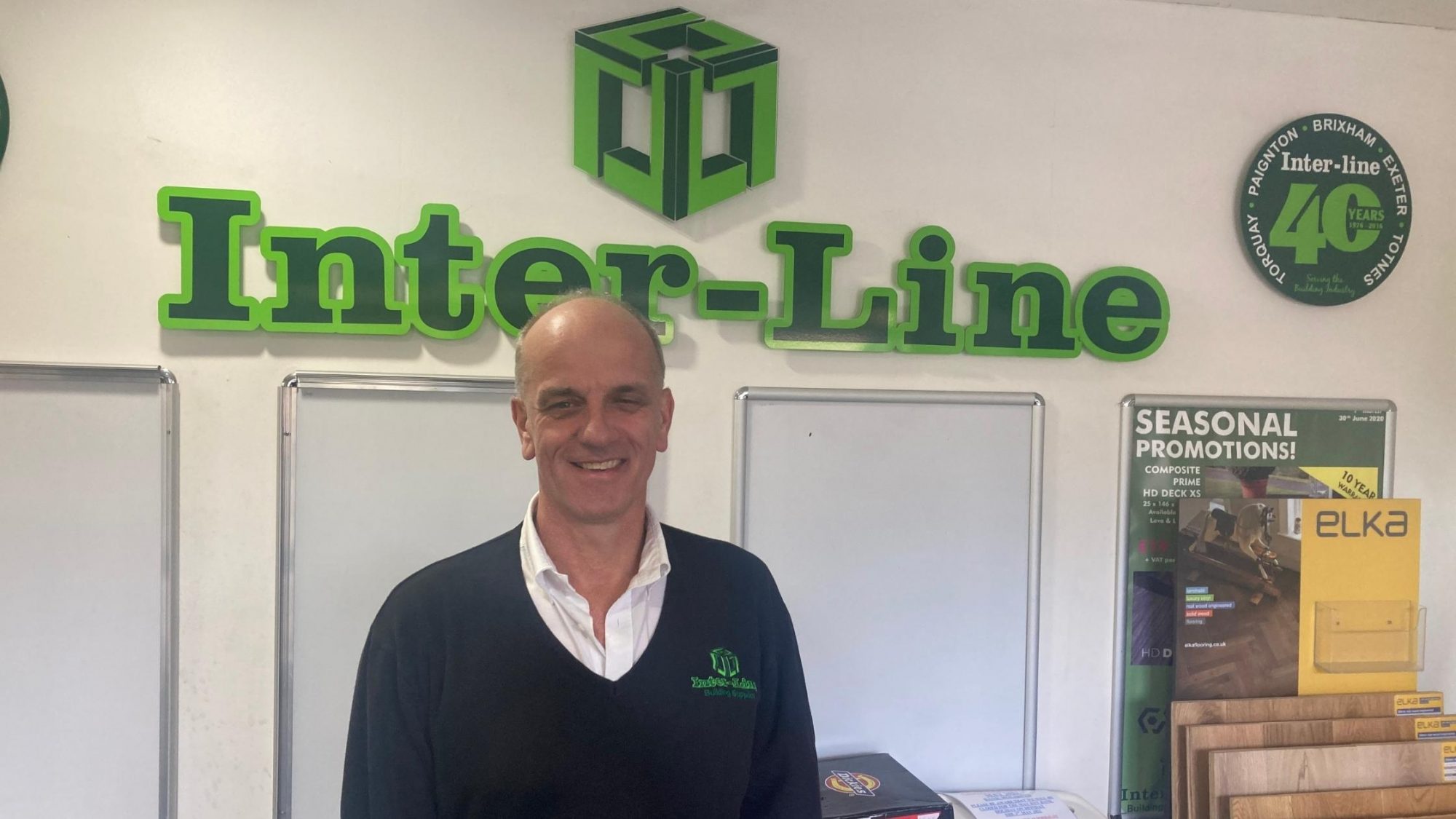 Inter-line staff member smiles in front of the Interline logo.