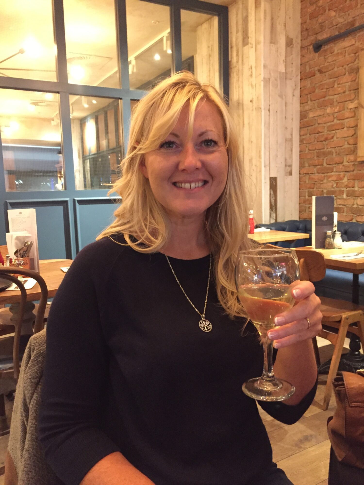 Rowcroft patient Jane Lloyd holding a glass of wine in a restaurant.