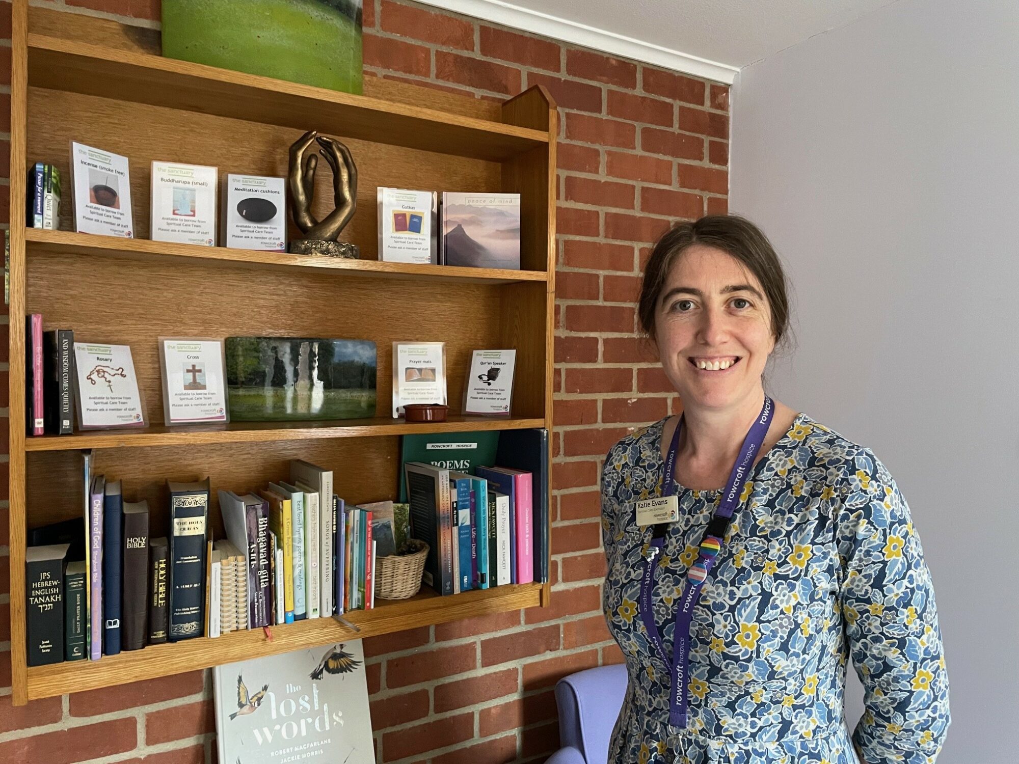 Katie Evans, Rowcroft's Spiritual Care Specialist, standing beside the hospice's multi-faith resources.
