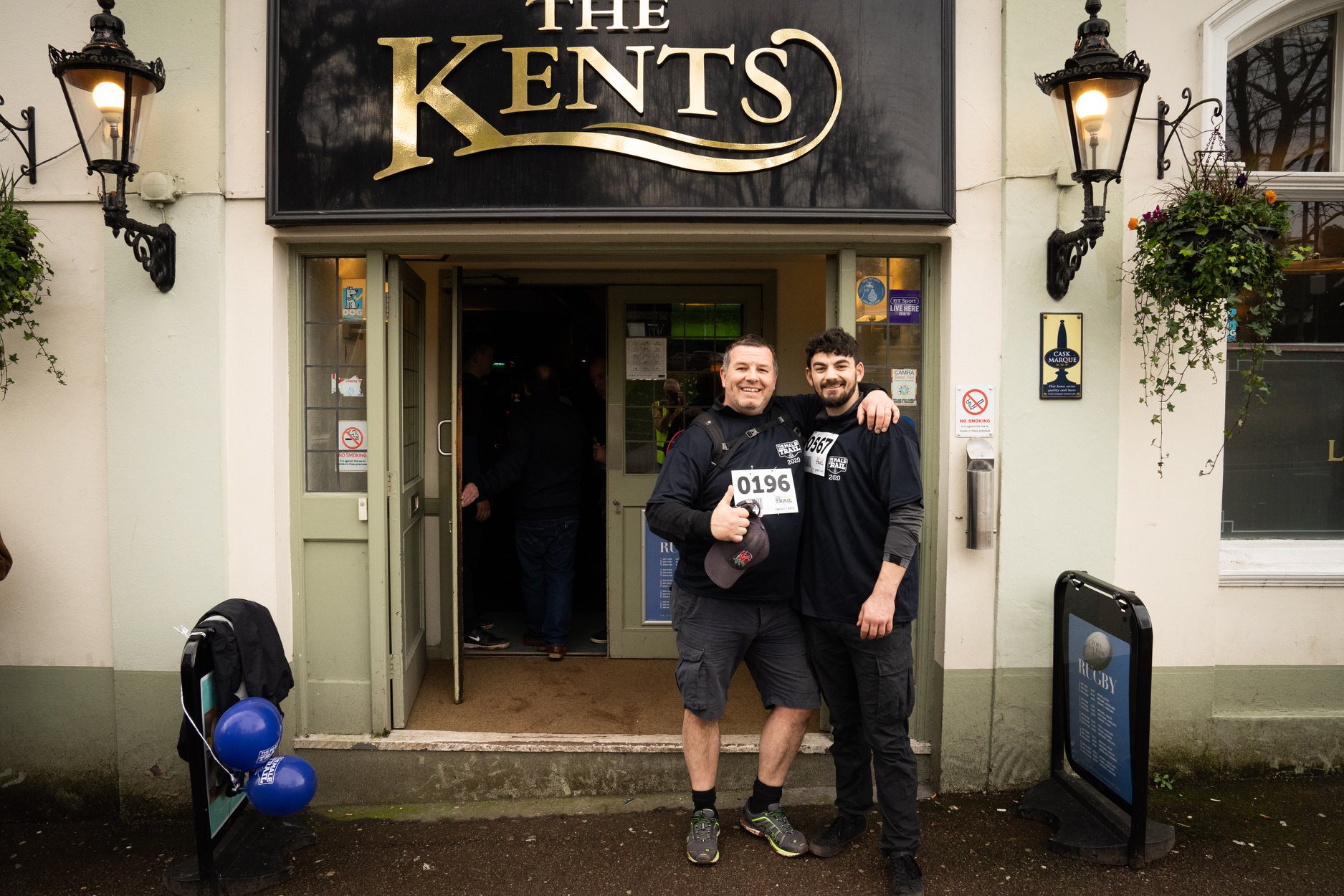 Two people who are taking part in the Male Trail pose for a photo outside of "The Kents"