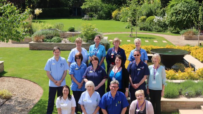 Rowcroft Hospice Staff stands outside for a team photo in the beautiful gardens.