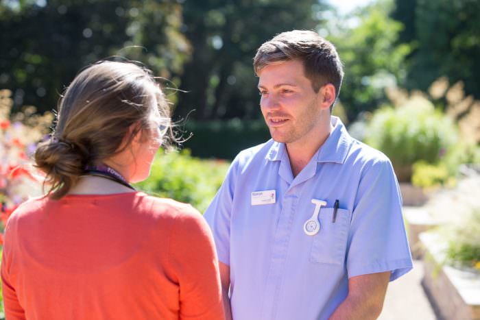 Two members of staff stand outside in the Rowcroft grounds.