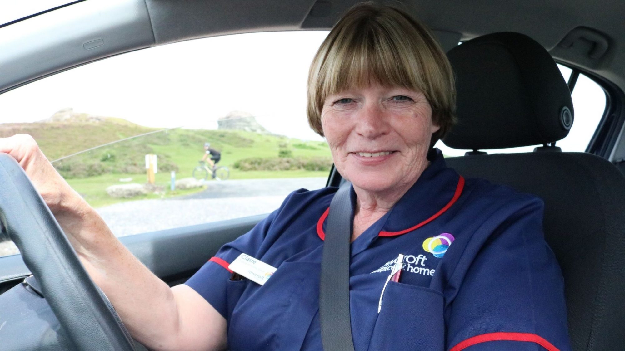 Rowcroft nurse, Claire smiles behind the wheel of a car.