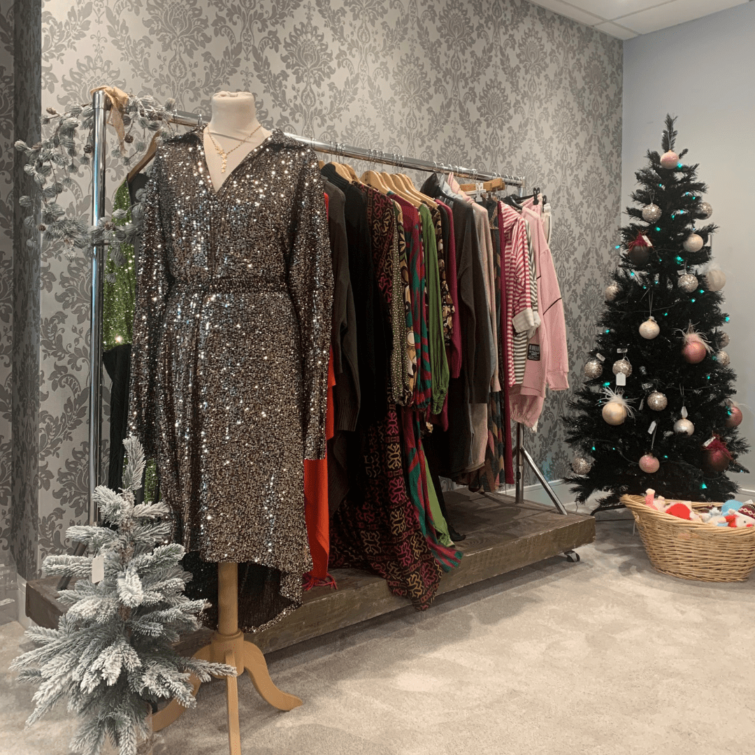 A dress on a shop model, a clothes rack and two Christmas tress.
