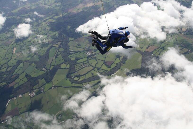 A birds-eye view of someone doing a tandem skydive.