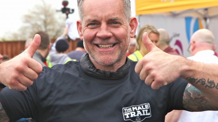 A participant in the Male Trail smiles at the camera with his thumbs up.